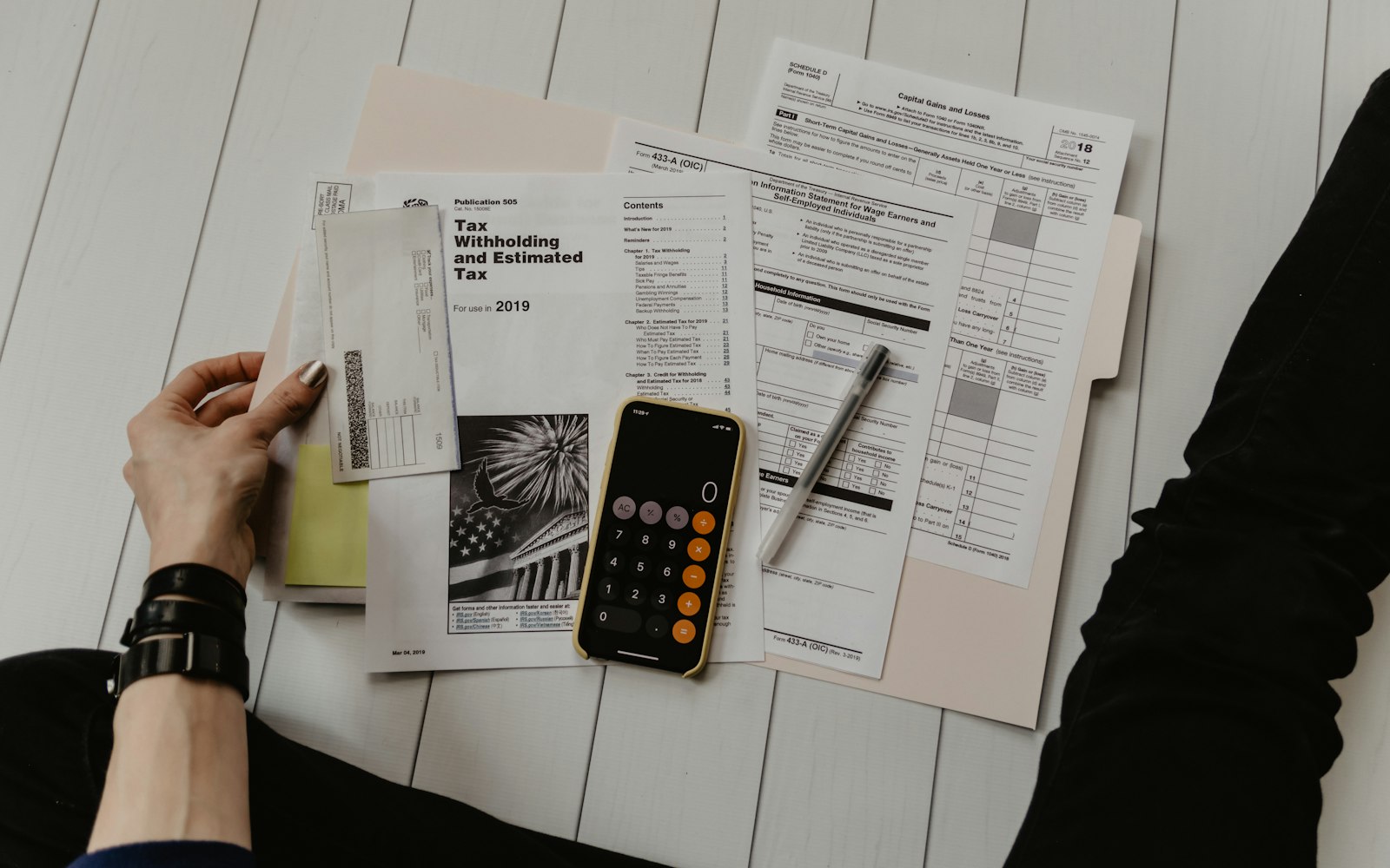 Tax forms, an envelope, and a calculator laid out neatly on a desk